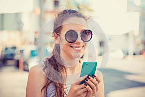 Young Woman in White Shirt Busy with her Mobile Phone While Walking a City Street