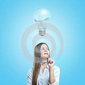 A young woman in a white shirt holding glasses in her hand with a 3d rendering of a bulb half-full with bubbling water.