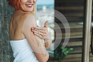 Young woman in white towel does body massage with organic natural scrab in bath, treat yourself photo