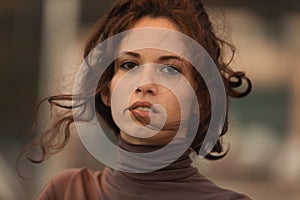 Young woman with wind-tousled hair, thoughtful gaze photo