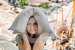 A young woman by the window annoyed by the building works outside covered my ears with a pillow. Noise concept