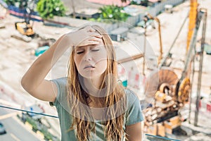 A young woman by the window annoyed by the building works outside. Noise concept