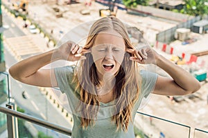 A young woman by the window annoyed by the building works outside. Noise concept