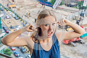 A young woman by the window annoyed by the building works outside. Noise concept