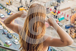 A young woman by the window annoyed by the building works outside. Noise concept