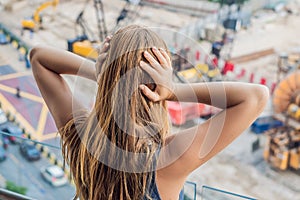 A young woman by the window annoyed by the building works outside. Noise concept