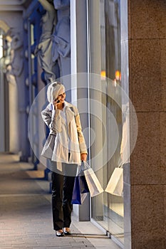 Young woman window shopping evening city