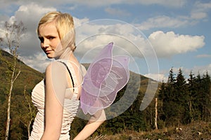 Young woman with wings against bright blue sky