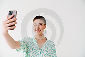 Young woman winking and taking selfie photo on cellphone