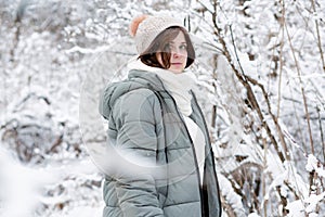 young woman in winter clothes among trees covered with snow, girl walking in snowy forest enjoying beautiful nature