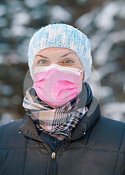 Young woman in winter jacket with pink disposable single use face virus mask