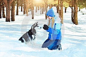 Young woman in winter snowy forest walking with her dog in a winter day. Friendship pet and human.