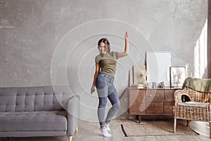 Young woman with wireless headphones dancing and listening to music at home
