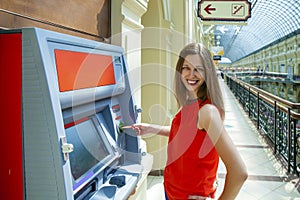 Young woman withdrawing money from credit card at ATM