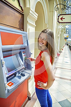 Young woman withdrawing money from credit card at ATM