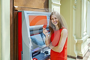 Young woman withdrawing money from credit card at ATM