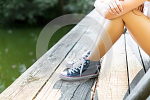 Young woman on a wooden bridge in jeans sneakers