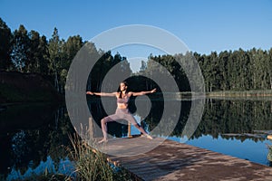 Young woman on wooden pier above forest lake scenery, folds her arms in a namaste gesture. Woman arms outstretched in