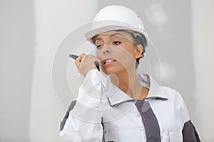 young woman worker on construction site using walkie talkie