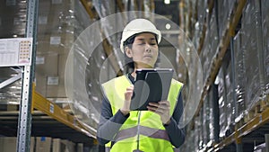 Young woman worker is using tablet during working process in modern warehouse.