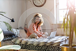 Young woman working in bed at home with laptop