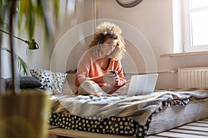 Young woman working in bed at home with laptop