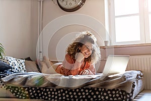 Young woman working in bed at home with laptop