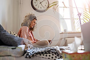 Young woman working in bed at home with laptop