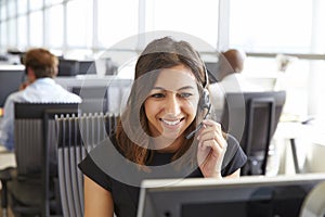 Young woman working in a call centre, holding headset