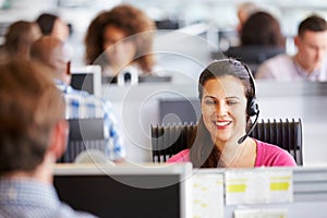 Young woman working in call centre, surrounded by colleagues