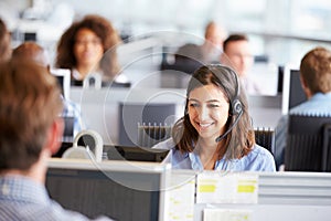 Young woman working in call centre, surrounded by colleagues