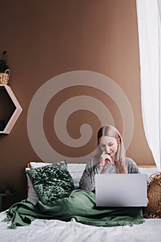 Young woman working on computer in bed. Relaxing at home. photo