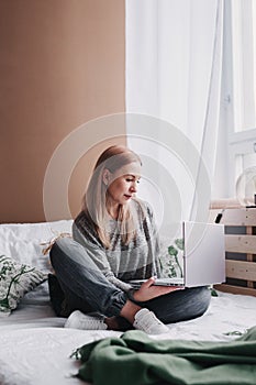 Young woman working on computer in bed. Relaxing at home. photo