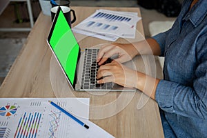 Young woman working on computer with graph sheet data