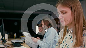 Young woman is working at the computer in the office with her workteam