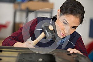 young woman working with hammer in industrial building