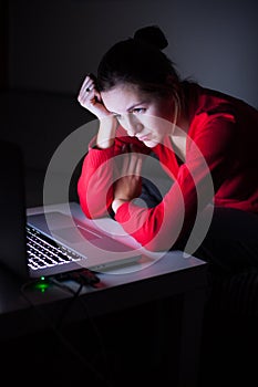 Young woman working on her laptop late at night