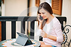 Young woman working from home on the balcony, using tablet pc