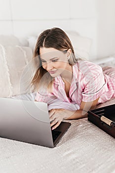 Young woman working at home in the bedroom during morning breakfast