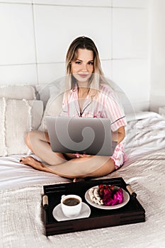 Young woman working at home in the bedroom during morning breakfast