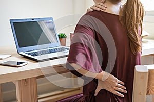 Young woman working at home and having back pain