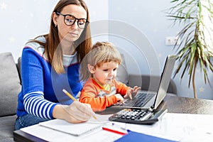 Young woman working at home with a laptop with a child on her lap