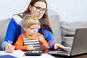 Young woman working at home with a laptop with a child on her lap