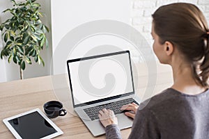 Young woman working at home. Student girl using laptop computer with empty blank screen