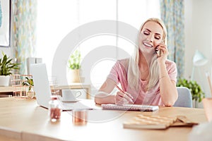 Young woman working at home, talking on mobile