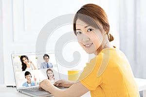 Young woman working at home and using laptop computer with video conference