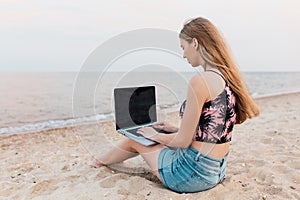 Young woman working with laptop on the beach