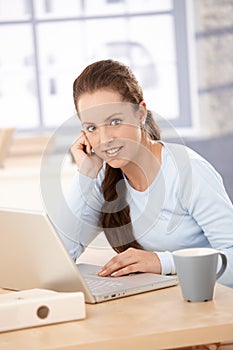 Young woman working on laptop in bright office