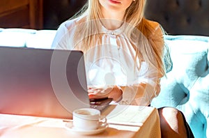 Young woman working with a laptop. Female freelancer connecting to internet via computer. Blogger or journalist writing