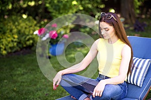 Young woman working on laptop in the garden